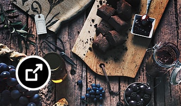 Rustic table with charcuterie cheese board, fruits, nuts, and cake