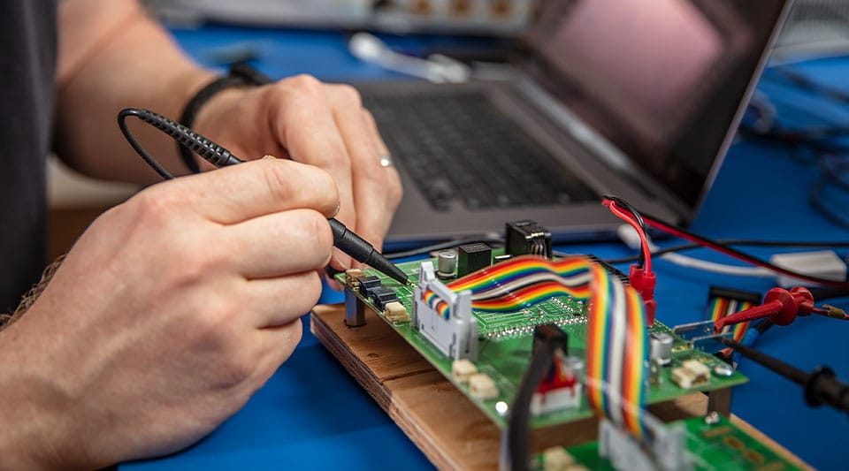 A person using PCB layout software while working on an electronic device